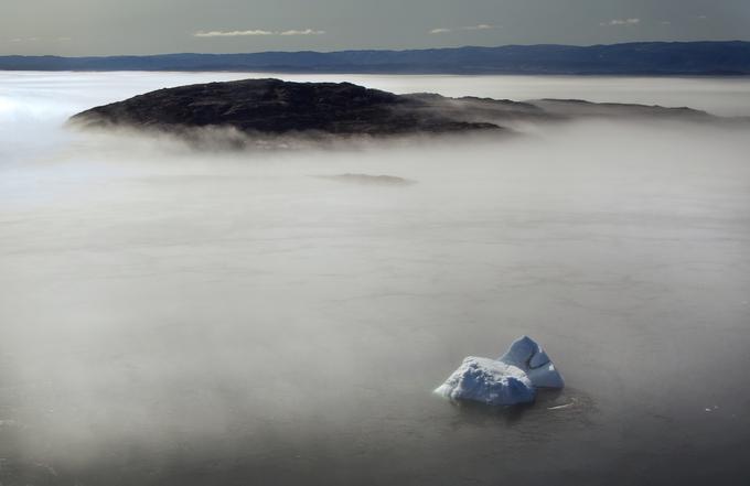 Velikanska osamljena ledena gora kuka iz jutranje meglice v zalivu Frobisher v Kanadi. | Foto: Reuters